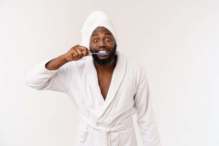 portrait of a happy young dark-anm brushing his teeth with black toothpaste on a white background.の写真素材