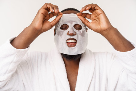 A young man with paper mask on face looking shocked with an open mouth, isolated on a white...