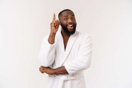 Black guy wearing a bathrobe pointing finger with surprise and happy emotion. Isolated over whtie background.の写真素材
