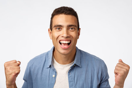 Cheerful, optimistic guy, clench fists and smiling broadly, having faith team will win, placed bet...