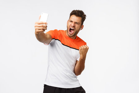Satisfied handsome male athlete in sports t-shirt winning award, sharing great news, achievement...