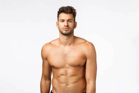 Waist-up shot confident good-looking, sexy young tanned man, athlete standing naked torso, squint, showing six-pack perfect body, train in gym, workout daily, lead active lifestyle. Bodybuilder promoの写真素材