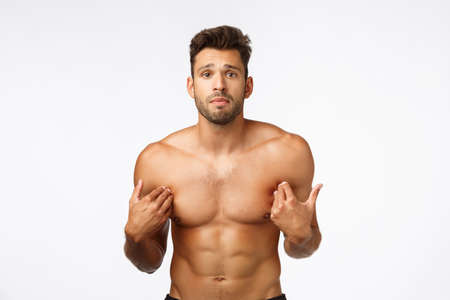 Cute upset, gloomy handsome shirtless sportsman with perfect body, six-packs abdominal abs, pointing himself, standing frustrated was accused something bad, posing distressed white backgroundの写真素材