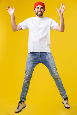 young casual man jumping for joy on yellow gold backgroundの写真素材