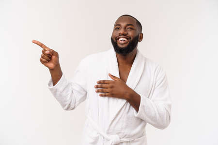 Black guy wearing a bathrobe pointing finger with surprise and happy emotion. Isolated over whtie background.の写真素材