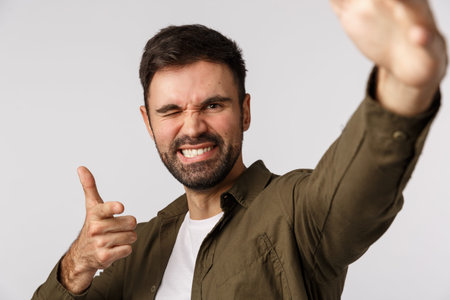 Cheeky and carefree confident handsome bearded guy, taking selfie as holding smartphone one hand,...