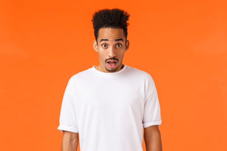 Startled, shocked african-american guy, drop jaw and stare camera with opened mouth fascinated...