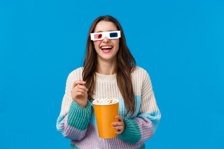 Girl watching comedy in cinema. Carefree happy young brunette woman in winter sweater, enjoying...