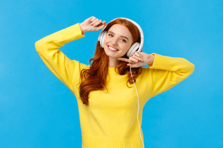 Technology, e-shopping and people concept. Modern good-looking redhead female in yellow sweater,...