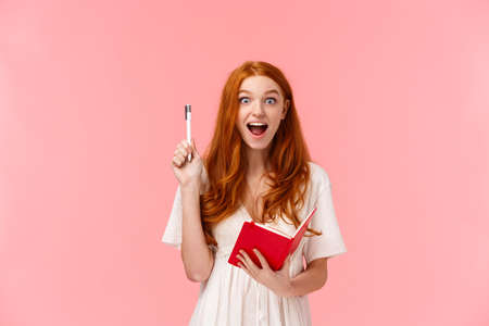 I got it. Girl found solution, have idea how solve homework exercises, raise pen up in eureka gesture, smiling relieved and pleased, holding notebook, writing something, remember answerの写真素材
