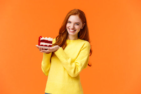 Cute friendly redhead woman holding tasty home-made piece cake and smiling, share bite, treat...