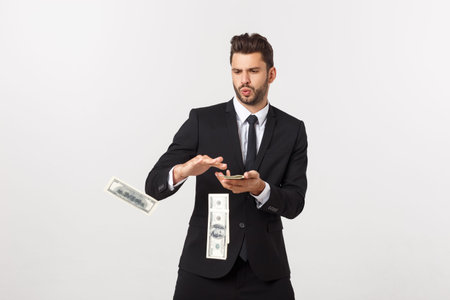 Portrait of a satisfied young businessman holding bunch of money banknotes isolated over white...
