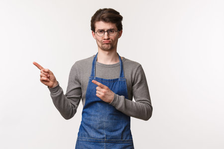 Portrait of reluctant and gloomy young guy working at coffee shop getting bored, hate clean tables...