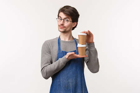 Portrait of charismatic handsome caucasian male coffee shop owner, barista giving two take-away drink and smiling, prepared tea for customers, give person his order, white backgroundの写真素材
