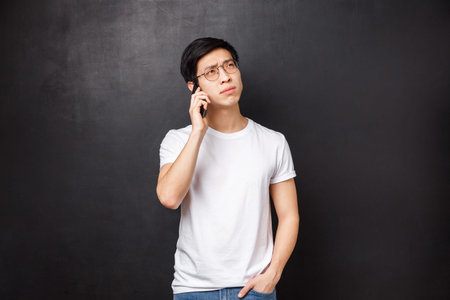 Technology, gadgets and people concept. Portrait of thoughtful young asian guy thinking over...