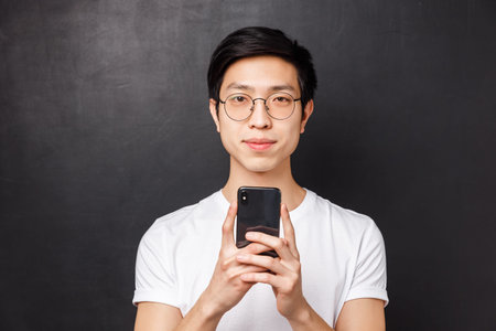 Technology, messaging and people concept. Close-up portrait of young asian male student smiling,...