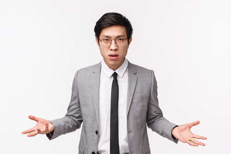 So what. Waist-up portrait of annoyed and skeptical, unimpressed serious-looking asian businessman spread hands sideways with dismay, puzzled cant understand what person wantsの写真素材