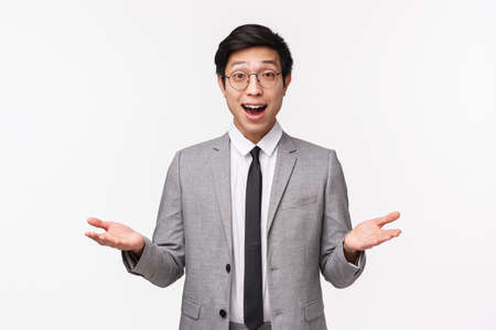 Waist-up portrait of handsome smart asian businessman in grey suit, explain team his project idea, gesturing with hands discuss something important during business meeting, white backgroundの写真素材