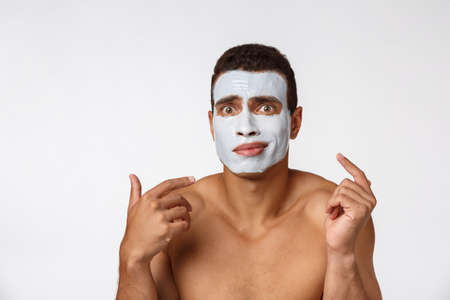 Photo of shirtless african american man smiling and applying face cream isolated over white backgroundの写真素材