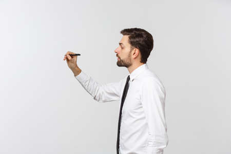A view of a young businessman holding a pen, ready to write something, isolated on white backgroundの写真素材