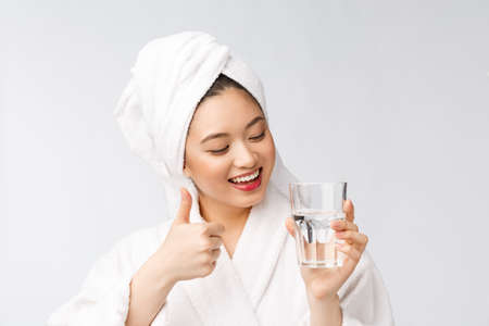 Healthy young beautiful woman drinking water, beauty face natural makeup, isolated over white background.の写真素材