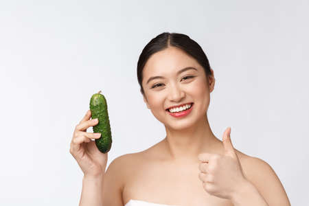 Asian young woman over isolated background holding cucumber.の写真素材