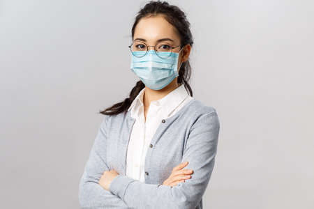 Covid19, virus, health and medicine concept. Portrait of young confident professional asian nurse, taking care of patients, wearing medical mask during quarantine coronavirus, cross hands chestの写真素材