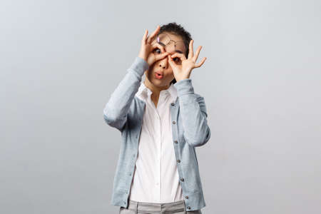 Lifestyle, people and emotions concept. Funny, playful silly asian girl fool around, playing with you, make glasses mask with fingers over eyse, peekabo at kid, staring camera joyfulの写真素材