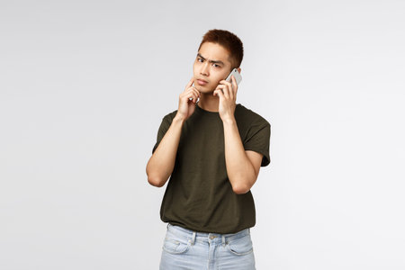 Technology, online lifestyle and communication concept. Thoughtful serious asian man talking on...