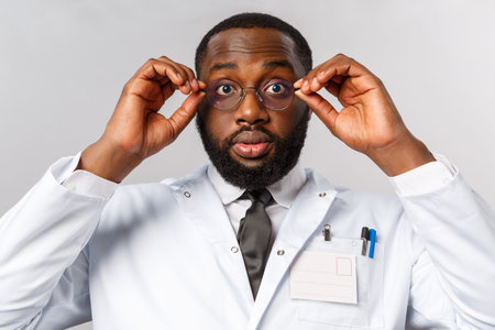 Healthcare, medicine and hospital treatment concept. Close-up portrait of shocked and impressed african-american doctor cant believe own eyes, put on glasses and stare astounded cameraの写真素材