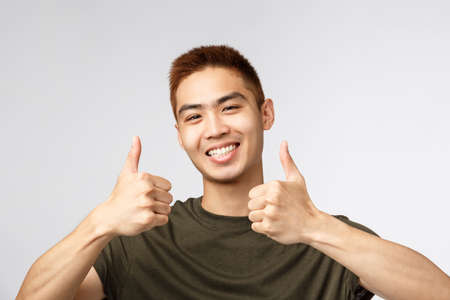 People, different expressions and lifestyle concept. Close-up portrait of happy, satisfied asian man leave positive review, show thumbs-up in approval, recommend product, like and agreeの写真素材