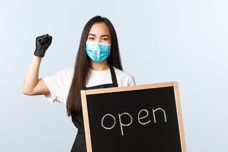 Small business, covid-19 pandemic, preventing virus and employees concept. Rejoicing cafe employee,...