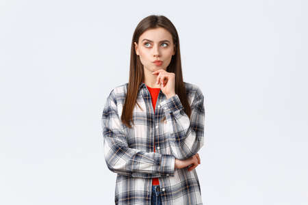 Lifestyle, different emotions, leisure activities concept. Smart woman in checked casual shirt searching solution, thinking and looking up, touch chin as pondering decision, making choiceの写真素材