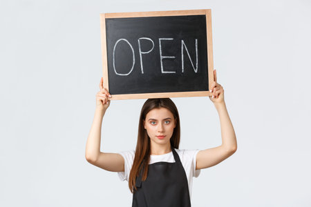 Grocery store employees, small business and coffee shops concept. Serious-looking young barista in...