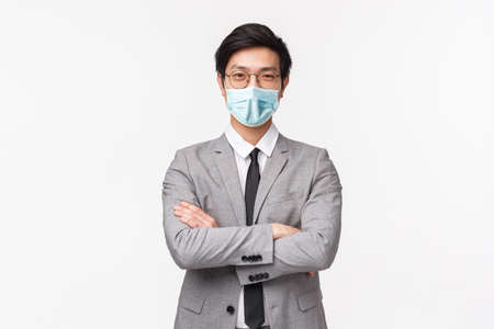 Waist-up portrait of confident smart and talented asian businessman, successful employer in grey suit, start own enterprise, earn money, cross hands over chest assertive smiling, white backgroundの写真素材