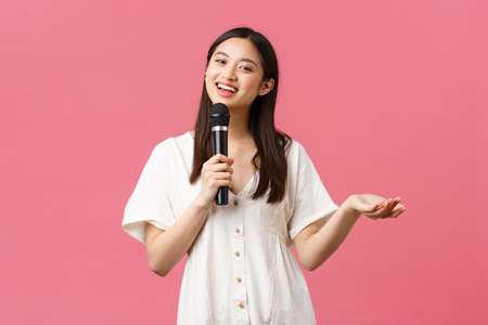 Leisure, people emotions and lifestyle concept. Charismatic pretty young asian girl making jokes, performing stand-up or give speech, singing karaoke with microphone, smiling cameraの写真素材