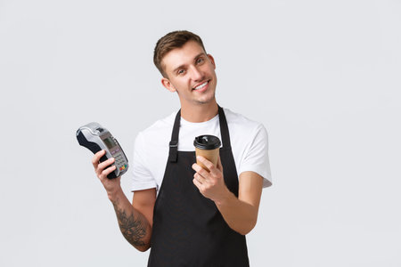 Small business owners, coffee shop and staff concept. Handsome smiling barista handing takeaway cup...