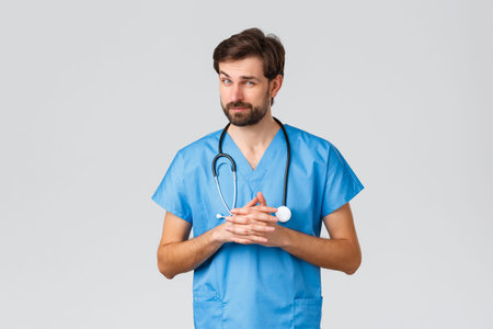 Covid-19, quarantine, hospitals and healthcare workers concept. Thoughtful handsome doctor in scrubs...