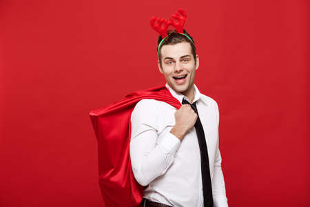 Christmas Concept - Handsome Business man celebrate merry christmas and happy new year wear reindeer hairband holding Santa red big bag.の写真素材