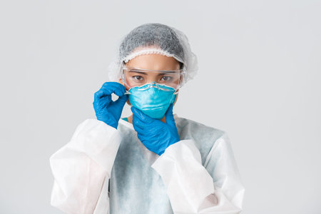 Covid-19, coronavirus disease, healthcare workers concept. Serious asian female doctor prepare enter...