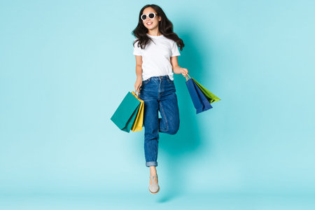 Fashion, beauty and lifestyle concept. Attractive carefree asian woman in sunglasses, holding...
