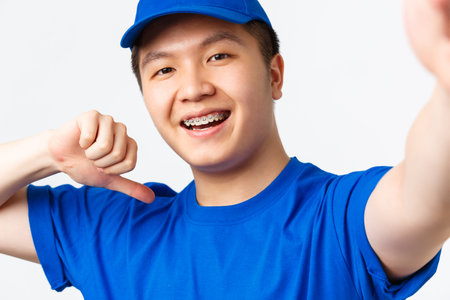 Online shopping, fast shipping, employees and home delivery concept. Smiling asian male courier in...