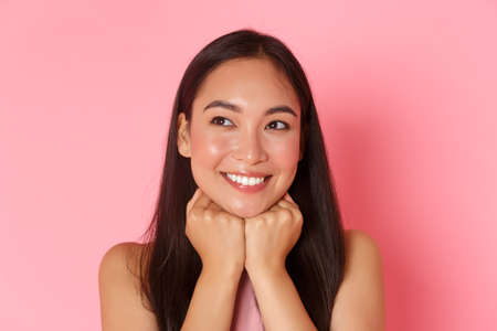 Beauty, fashion and lifestyle concept. Close-up of dreamy and romantic, attractive asian girl daydreaming, leaning face and looking upper left corner pleased, picturing moment in bubble chatの写真素材