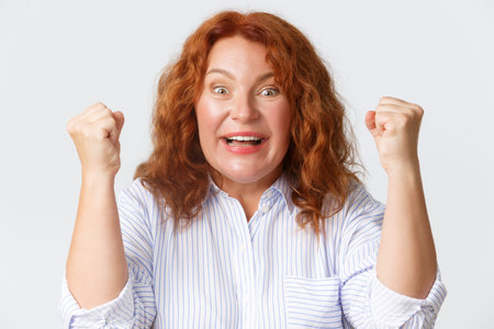 People, emotions and lifestyle concept. Close-up of lucky winning middle-aged redhead woman...