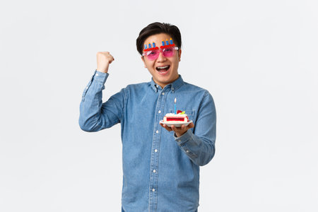 Celebration, holidays and lifestyle concept. Upbeat positive asian guy in funny party sunglasses...