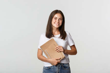 Happy smiling girl student holding notebooks, apply for courses or universityの写真素材