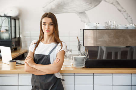 Coffee Business owner Concept - Portrait of happy attractive young beautiful caucasian barista in apron with confident looking at camera in coffee shop counter.の写真素材