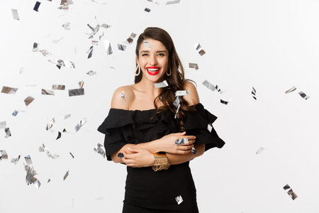 Happy woman celebrating winter holidays, smiling cheerful, partying on New Year with confetti,...