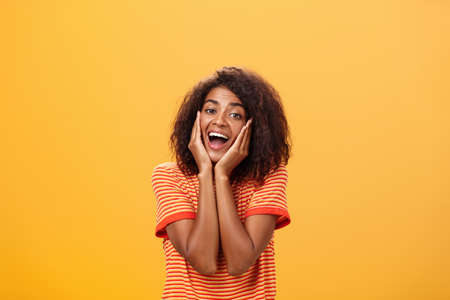 Dreamy good-looking stylish young african female with curly hairstyle sighing leaning head on palms gazing with affection and admiration at camera being in love imaging prince on white horseの写真素材