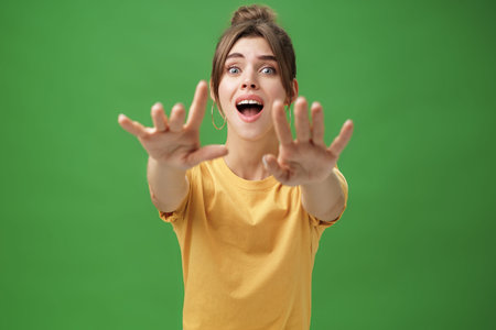 Excited and addicted goog-looking young woman reaching hands forward to camera with reckless look...